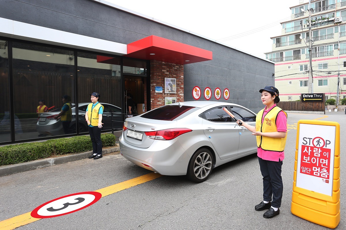 한국맥도날드 드라이스스루(DT) 매장 앞에서 직원들이 교통안전 지도를 하고 있다. [한국맥도날드 제공]