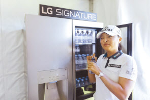 아문디에비앙챔피언십 1번홀 내 LG 시그니처 체험존에서 고진영 선수가 냉장고 안의 에비앙 생수를 꺼내 마시며 직접 제품을 체험해보고 있다. [LG전자 제공]