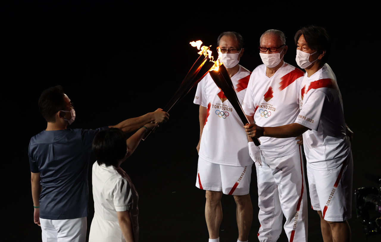 23일 일본 도쿄 신주쿠 국립경기장에서 열린 2020 도쿄올림픽 개막식에서 일본 프로야구 감독 및 선수 출신인 오 사다하루(왼쪽부터), 나가시마 시게오, 마쓰이 히데키가 코로나19 치료를 담당하는 의사 및 간호사에게 성화를 전달하고 있다. [연합]