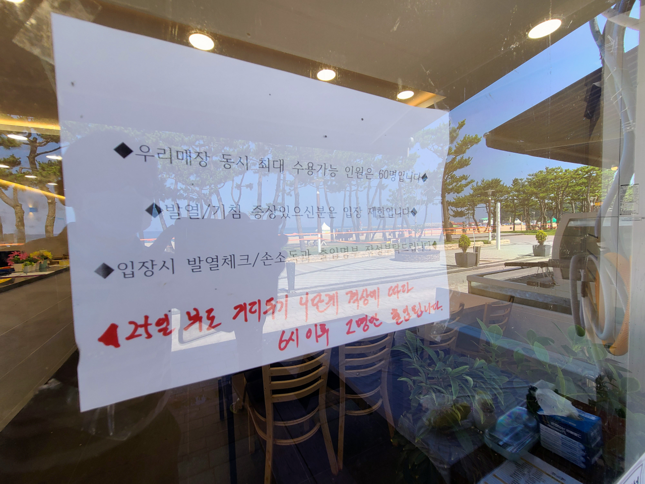 강원 양양군이 25일부터 사회적 거리두기를 4단계로 높인 가운데 낙산해수욕장 인근 한 음식점에 오후 6시 이후 2명만 사적 모임이 허용된다는 내용이 추가로 표시된 안내문이 붙어 있다. [연합]