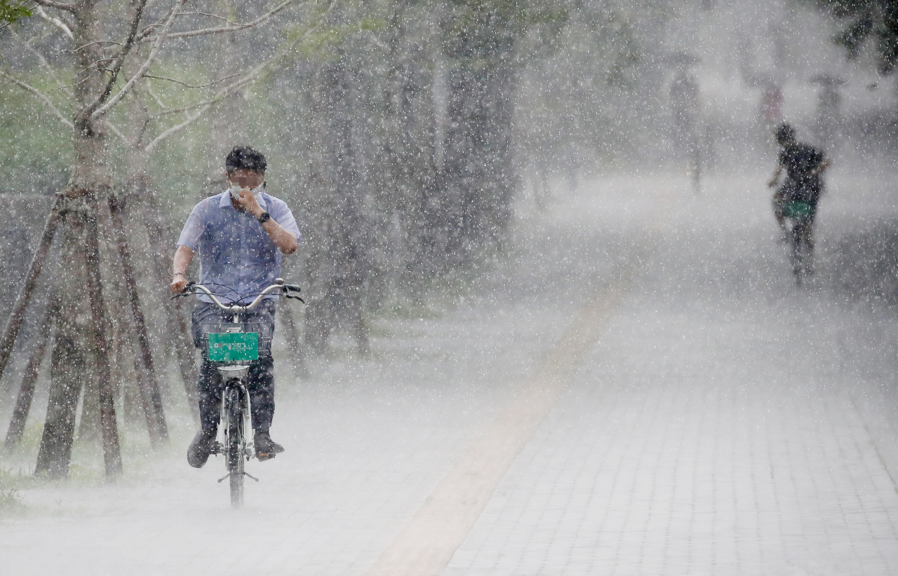 A Ddareungi user rides the rental bike through rain late last month. (Yonhap)