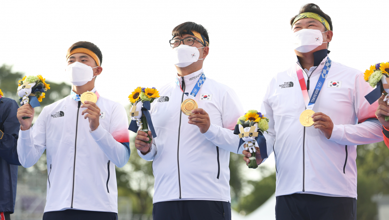 26일 도쿄올림픽 남자 양궁 단체전에서 우승한 김제덕(왼쪽부터), 김우진, 오진혁이 일본 유메노시마 공원 양궁장 시상대에서 금메달을 들어 보이고 있다. 연합뉴스