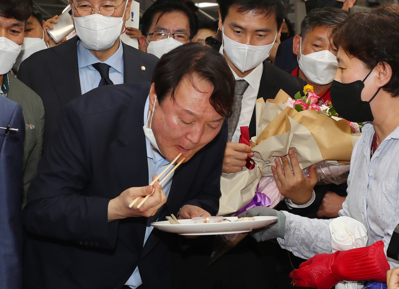 윤석열 전 검찰총장이 27일 오후 부산 중구 자갈치시장을 방문해서 한 상인이 건넨 전복회를 맛보고 있다. [연합]