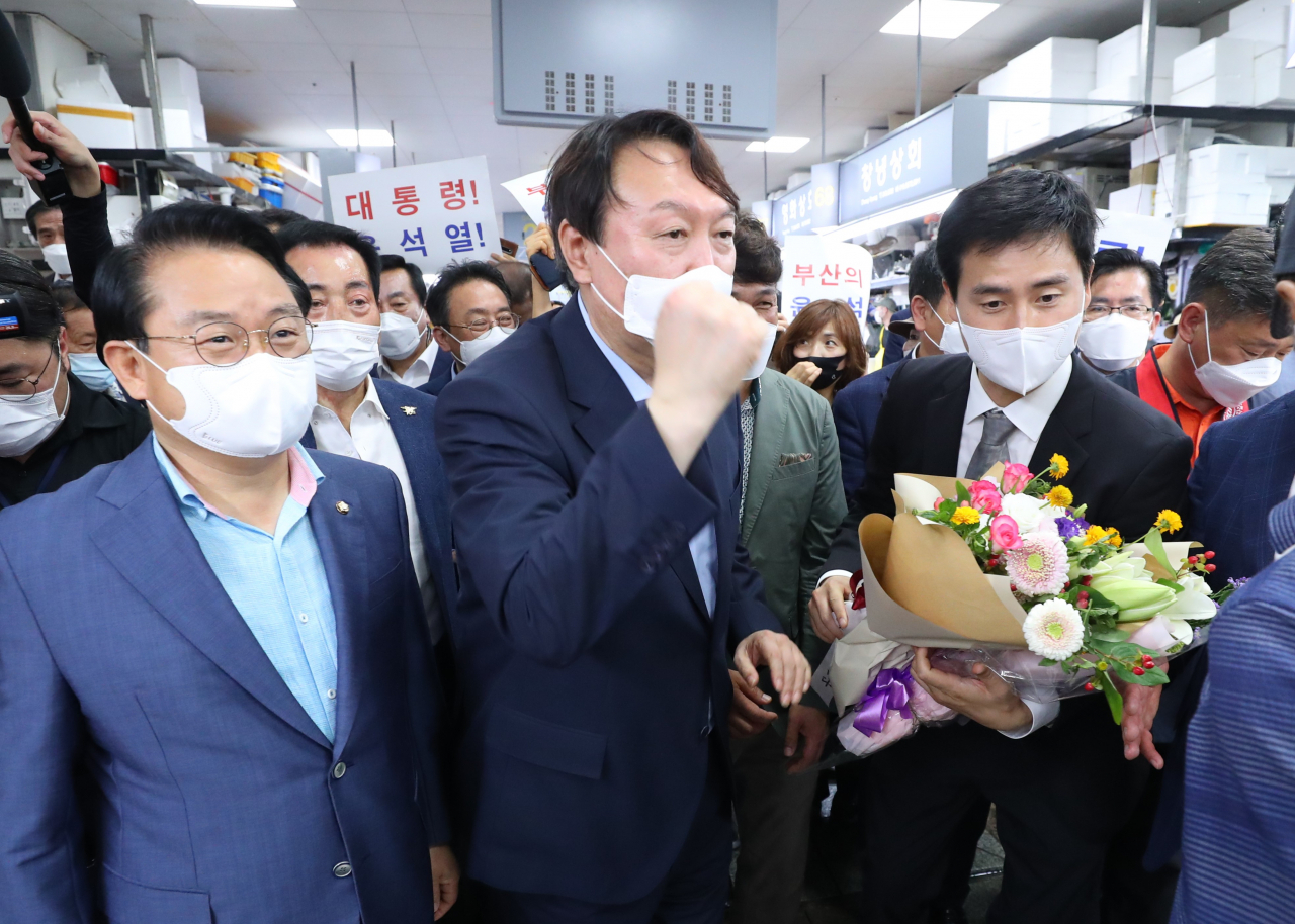 윤석열 전 검찰총장이 지난 27일 오후 부산 중구 자갈치시장을 방문해 상인들의 응원을 듣고 주먹을 치켜올리고 있다. [연합]