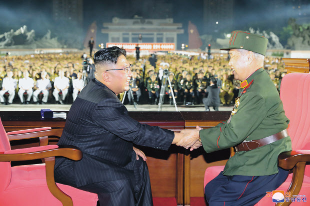 김정은 북한 국무위원장이 27일 평양 조국해방전쟁승리기념탑 앞에서 열린 제7차 전국노병대회에서 노병 참석자와 마주 앉아 악수를 하고 있다. 조선중앙통신의 28일 보도에 따르면 이날 대회에는 김 위원장을 비롯해 최룡해 최고인민회의 상임위원장, 조용원 노동당 조직비서, 김덕훈 내각 총리 등과 군 고위 간부들이 참석했다. [연합]