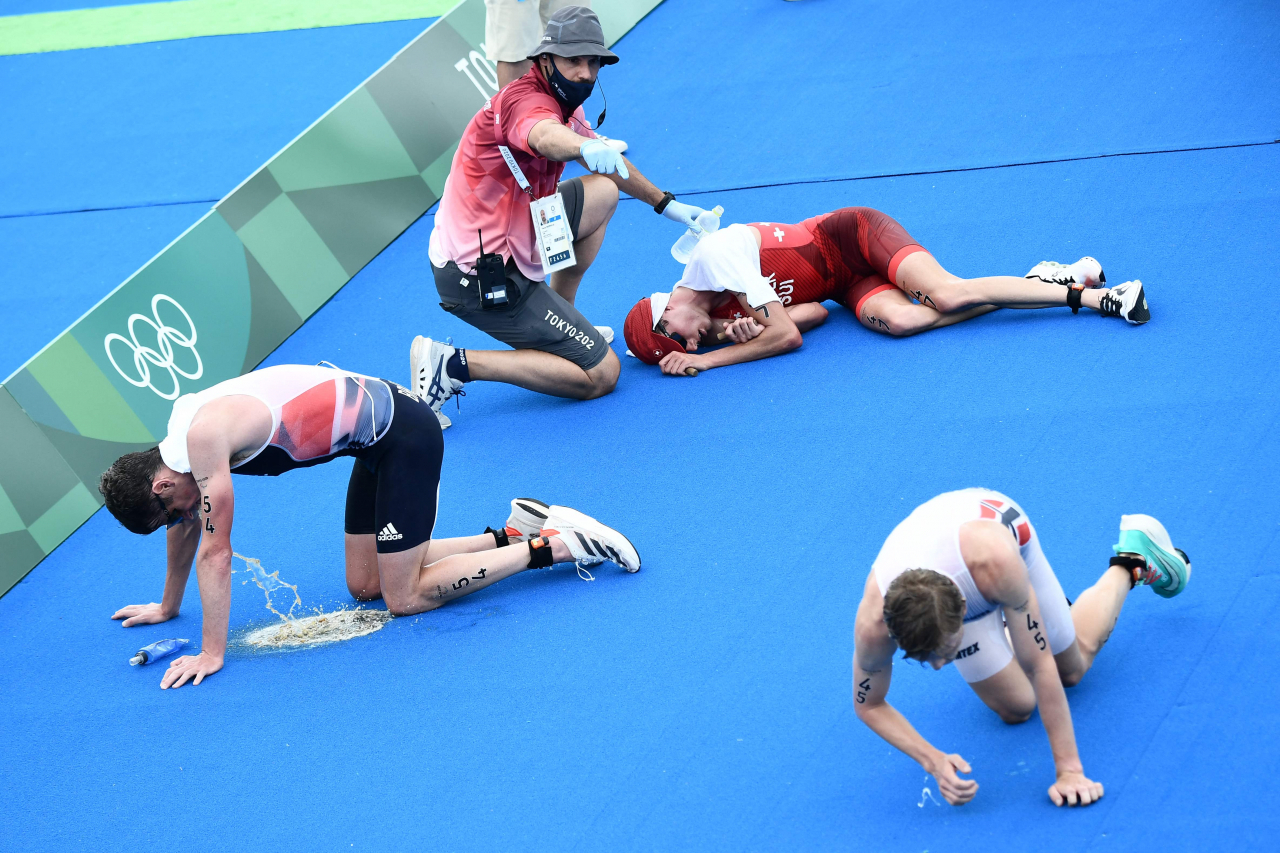 지난 26일 일본 도쿄 오다이바해상공원서 열린 도쿄올림픽 트라이애슬론(철인 3종 경기) 남자 개인전 경기를 마친 선수들이 바닥에 쓰러져 있다. 이날 선수들은 무더위에 지쳐 쓰러졌으며, 일부는 구토를 하기도 했다. 미국 야후스포츠의 칼럼니스트 댄 웨트젤은 일본이 올림픽 개최를 위해 공식 제안서에 쓴 문구인 '기후가 온화하고 화창하며, 선수들이 최고의 기량을 펼치기에 이상적인 날씨'를 지적하며 일본이 도쿄의 여름 날씨를 속였다고 비판했다. [연합]