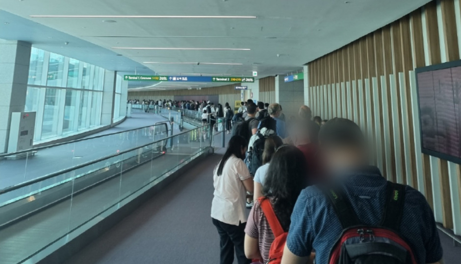 24일 오후 4시10분께 인천국제공항 제2여객터미널에 미국발 항공기에서 내린 탑승객들이 입국심사를 받기 위해 검역소로 이동하기 위해 길게 줄을 서 있다. 외국인과 한국인이 다닥다닥 앞뒤로 붙어 있는 모습도 보인다. [독자 제공]