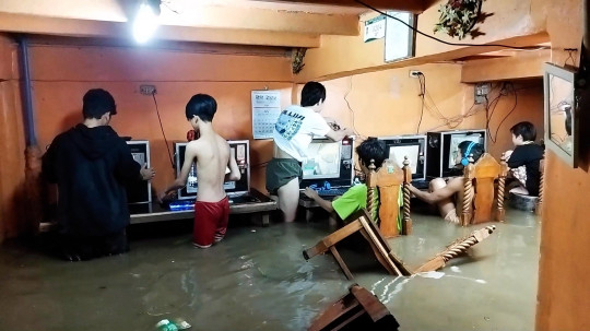 필리핀의 한 인터넷 카페에서 10대 소년들이 태풍·침수로 물이 무릎까지 차올랐는데도 게임을 즐기고 있다. [메트로 캡처]