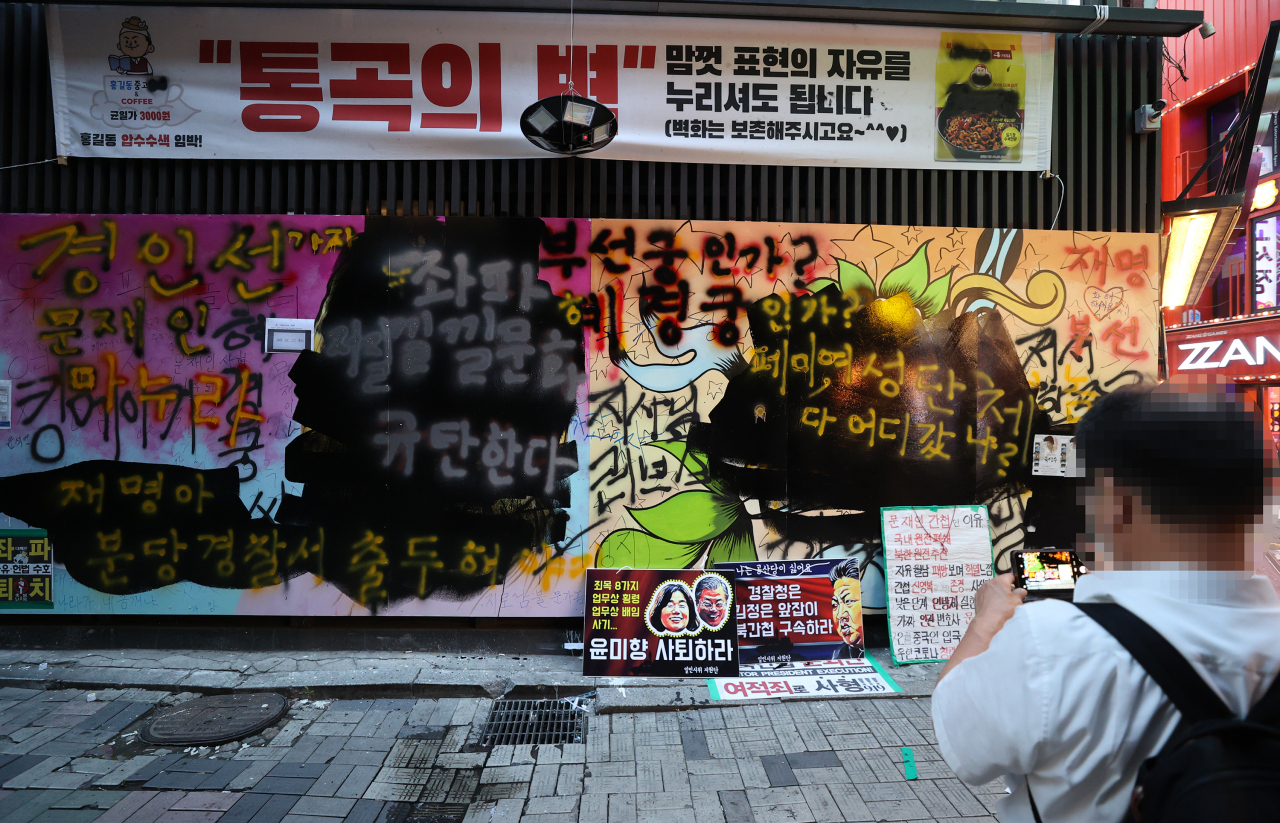 서울 종로구 관철동의 한 중고서점 앞에 윤석열 전 검찰총장 아내 김건희 씨를 비방하는 내용의 벽화가 게시돼 논란이 이어지는 가운데 한 유튜버가 벽화 위에 검은색 페인트로 덧칠했다. 사진은 31일 검은색 페인트로 덧칠된 벽화. [연합]