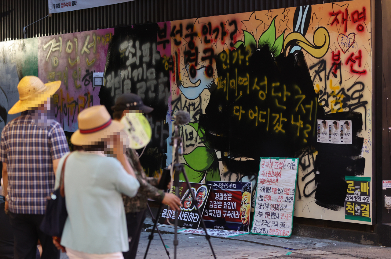 서울 종로구 관철동의 한 중고서점 앞에 윤석열 전 검찰총장 아내 김건희 씨를 비방하는 내용의 벽화가 게시돼 논란이 이어지는 가운데 한 유튜버가 벽화 위에 검은색 페인트로 덧칠했다. 사진은 지난달 31일 검은색 페인트로 덧칠된 벽화. [연합]