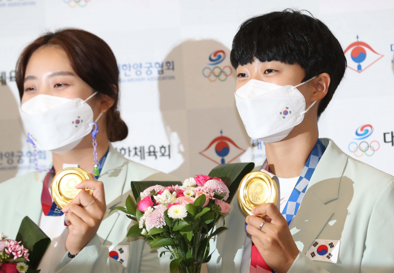 2020 도쿄올림픽 양궁 대표팀 안산(오른쪽), 장민희가 1일 오후 영종도 인천국제공항을 통해 귀국한 뒤 금메달을 들어보이고 있다. [연합]