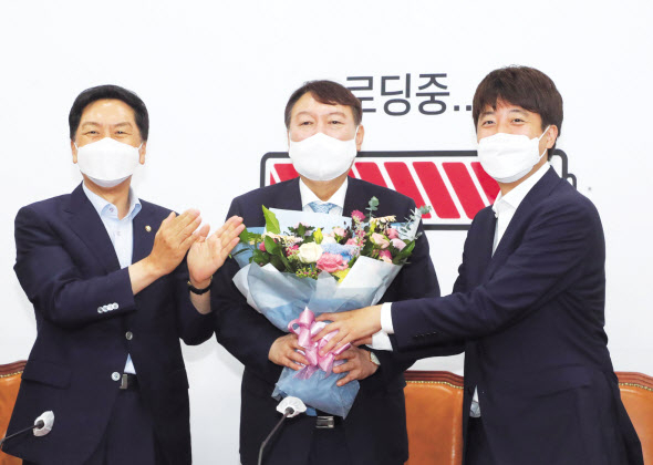 윤석열 대선 예비후보(가운데)가 2일 오전 서울 여의도 국회에서 국민의힘 이준석 대표(오른쪽)로부터 환영 꽃다발을 받고 있다. 이상섭 기자