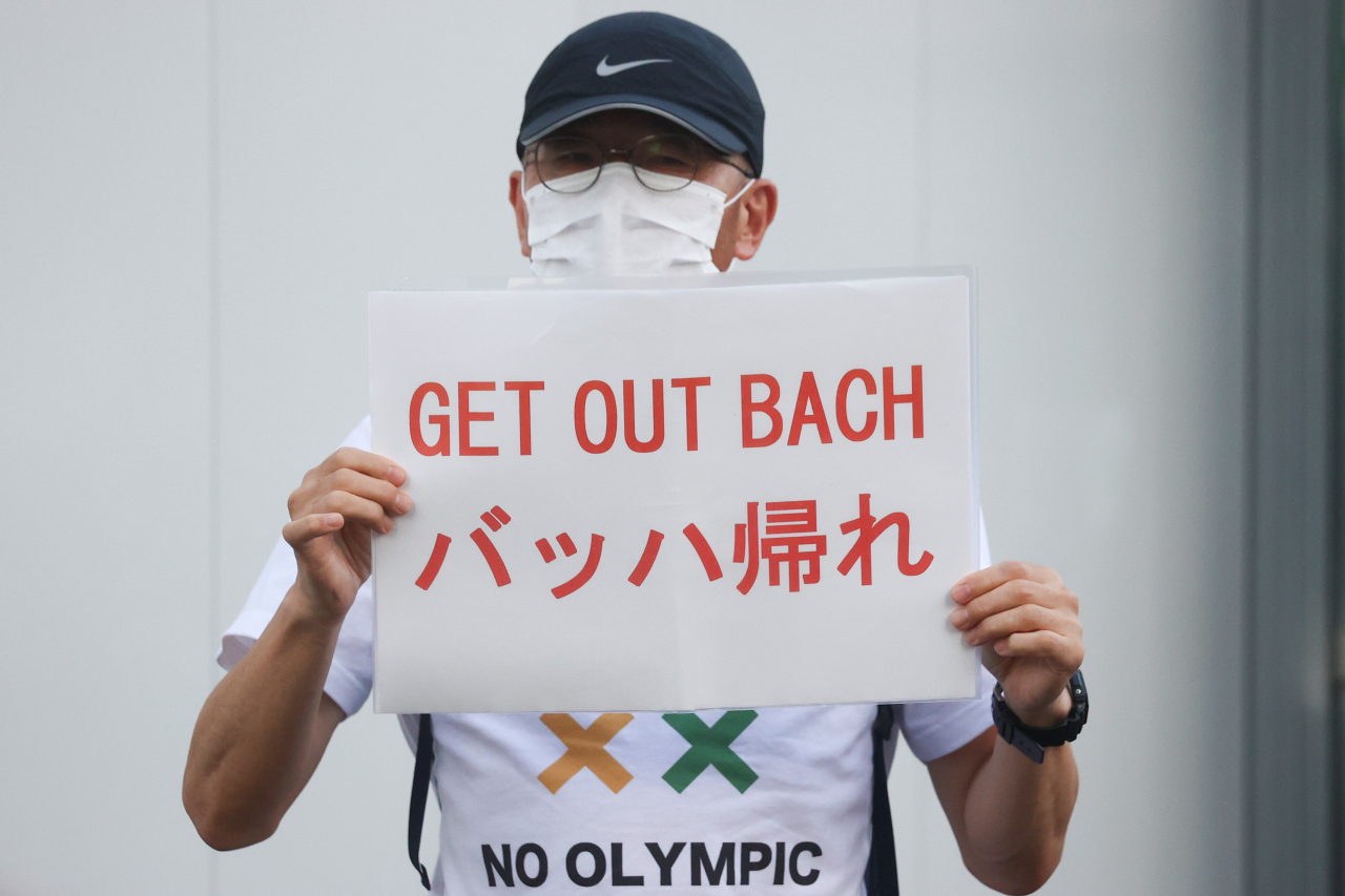 도쿄올림픽 개최에 반대하는 한 일본인이 ‘토마스 바흐 IOC 위원장은 떠나라’는 플래카드를 들고 있다. [로이터]
