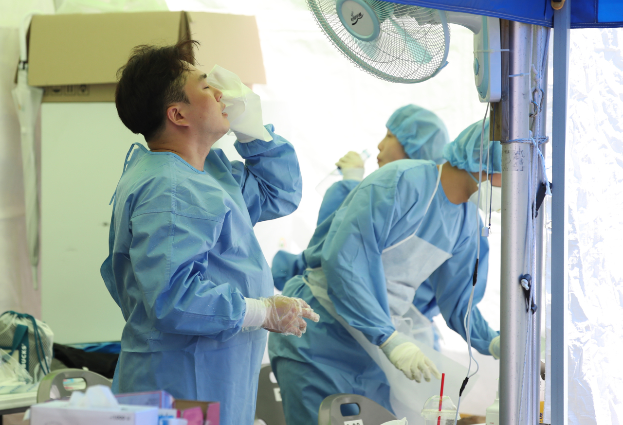 A health worker at a makeshift COVID testing center in western Seoul wipes sweat off his face on a scorching July afternoon. (Yonhap)