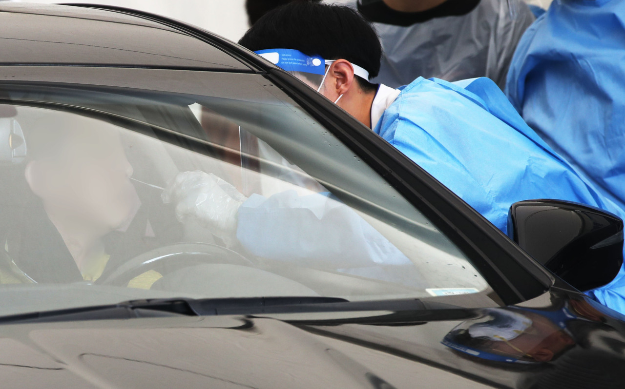 A medical staff worker collects sample at a temporary drive-through COVID-19 testing center made in Jungnang-gu, eastern Seoul, on Wednesday. (Yonhap)