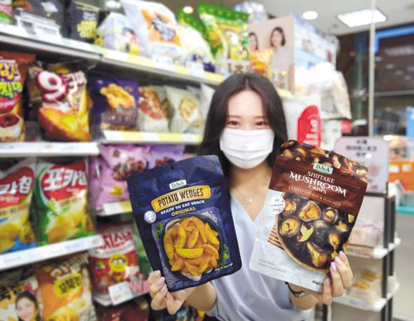 GS25 모델이 ‘DJ&A머쉬룸칩30G’와 ‘DJ&A포테이토웨지스오리지널65G’를 소개하고 있다. [GS25 제공]