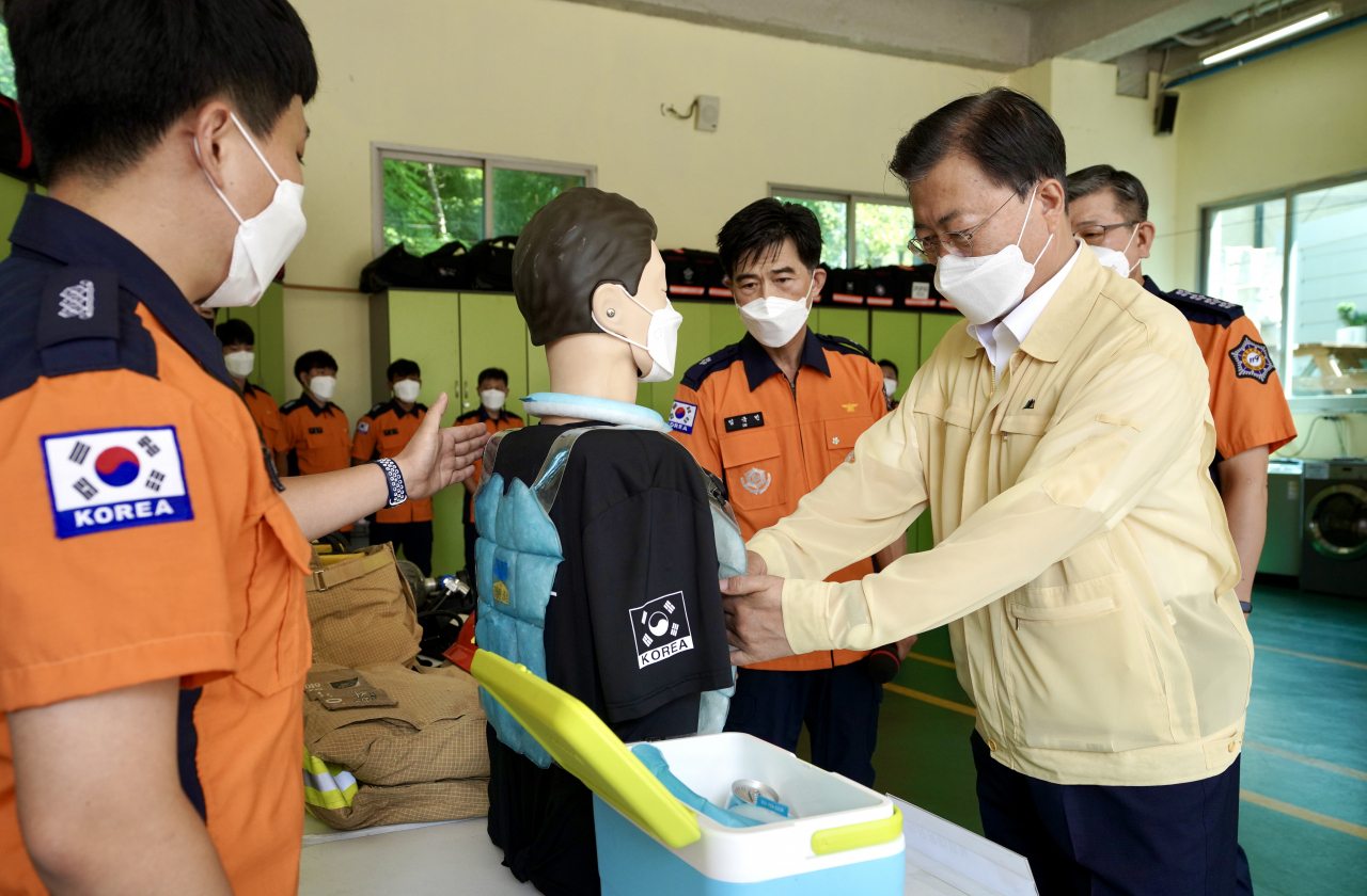 문재인 대통령이 6일 오전 경기도 용인소방서를 방문해 용인소방서 내 시민안전체험센터에서 무더위속 소방관의 노고를 격려하고 얼음팩 조끼를 살펴보고 있다. [연합]