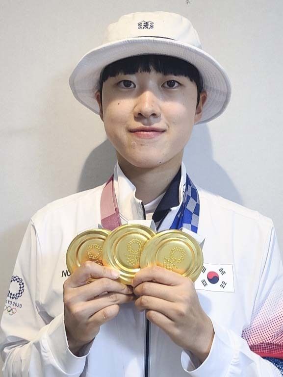 3관왕을 차지한 안산 선수가 도쿄 올림픽 선수촌에서 세개의 금메달을 목에 걸고 기념 촬영을 하고 있다.
