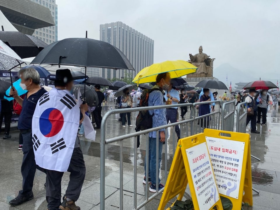 지난해 8월 15일 오후 서울 종로구 광화문광장에서 열린 ‘문재인 퇴진 8·15 범국민 대회’에 참가한 시민들이 ‘도심 내 집회금지’ 표지판 옆을 지나가고 있다. 신주희 기자