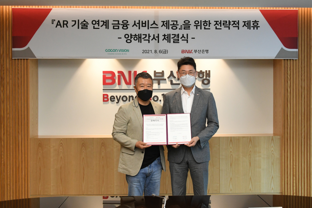 BNK부산은행이 지난 6일 오후, 부산은행 본점에서 미디어 콘텐츠 기술 전문기업 코코아비전과 AR(증강현실) 기술과 금융을 연계한 새로운 서비스를 제공하기 위해 업무 협약식을 개최했다고 밝혔다.(사진 오른쪽부터 부산은행 이주형 디지털금융본부장, ㈜코코아비전 최영주 대표이사) [부산은행 제공]