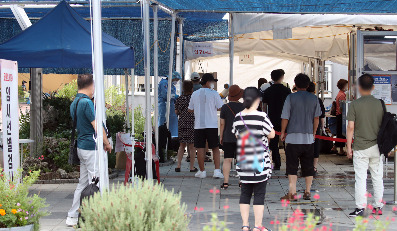 People are in line Tuesday to get tested for COVID-19 at a temporary testing center made in Guro-gu, southwestern Seoul. (Yonhap)