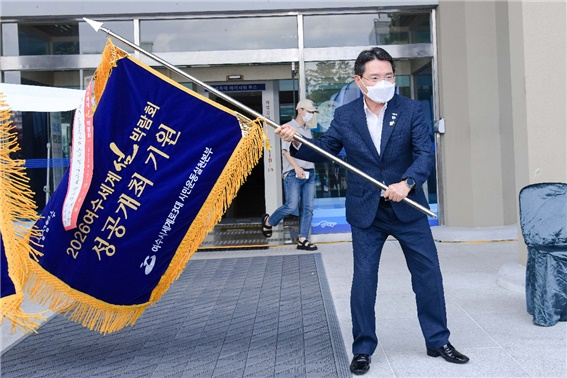 11일 권오봉 시장이 본청 앞에서 2026여수세계섬박람회 기원기를 힘차게 흔들며 성공 개최를 다짐하고 있다. [여수시 제공]