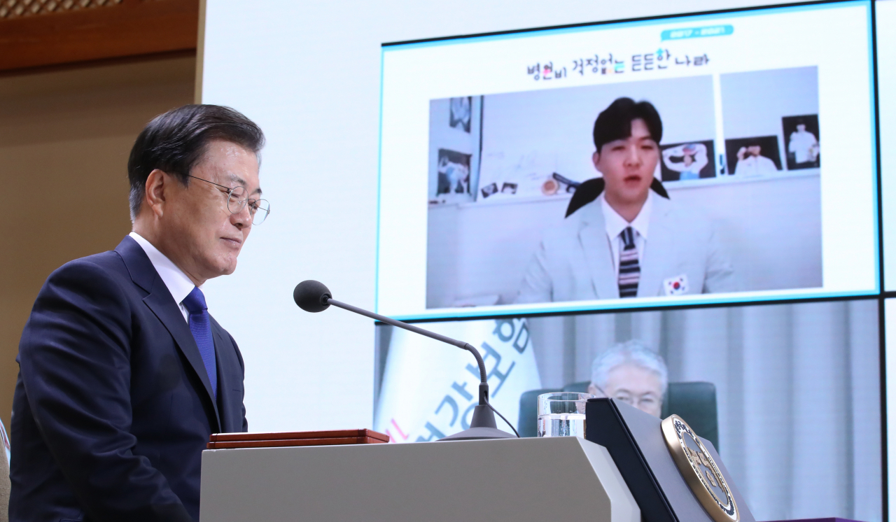 문재인 대통령이 12일 청와대 본관에서 화상을 통해 열린 건강보험 보장성 강화대책 4주년 성과 보고대회에서 도쿄올림픽 태권도 동메달리스트 인교돈 선수의 보장성 강화 수혜 사례 발표를 듣고 있다. [연합]
