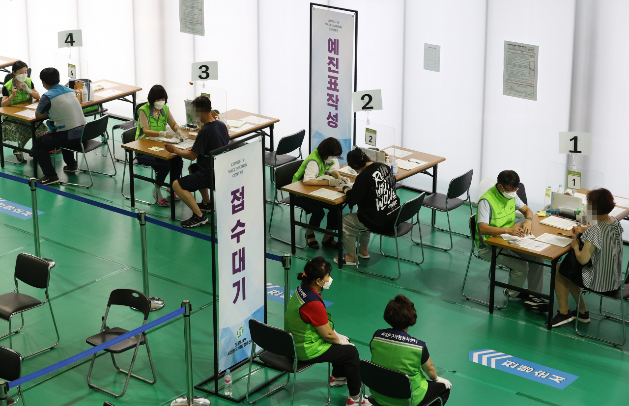 13일 오후 서울 서대문구 북아현문화체육센터에 마련된 예방접종센터에서 시민들이 예진표를 작성하고 있다. [연합]