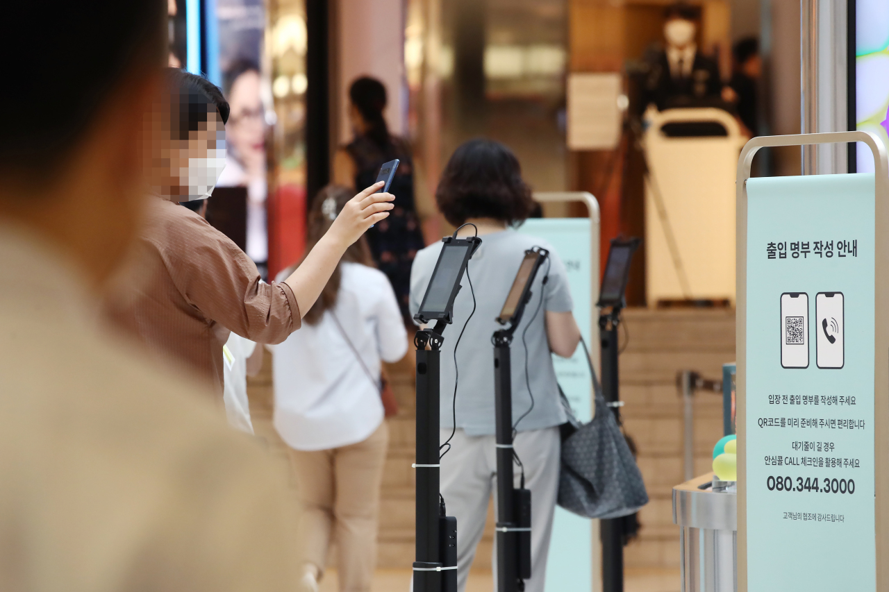 A customer checks in with a temporary QR code embedded in  smartphone before entering a department store in Seoul. Korea‘s QR check-in mandates led to wider adoption of online payment and banking. (Yonhap)