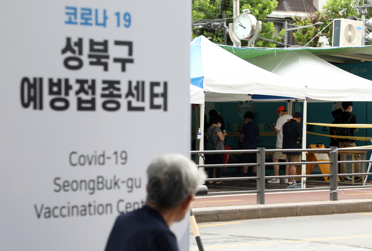18일 성북구 예방접종센터에서 한 시민이 길 건너 선별진료소를 바라보고 있다. 코로나19 예방접종대응추진단에 따르면 2차 접종까지 모두 마친 사람은 총 1049만1866명으로, 인구 대비 20.4%다. 1차 접종자는 2378만511명으로, 인구 대비 46.3%다. [연합]