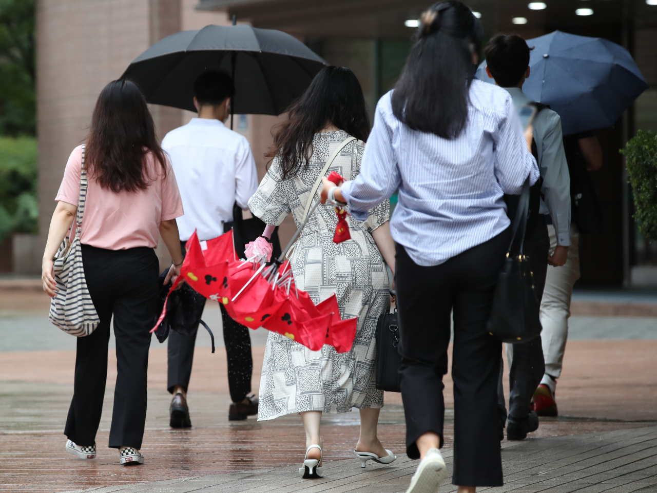 밤새 내린 비가 출근길에 멈춘 18일 오전 서울 중구에서 우산을 쓰고 출근하던 직장인이 우산을 접고 있다. [연합]