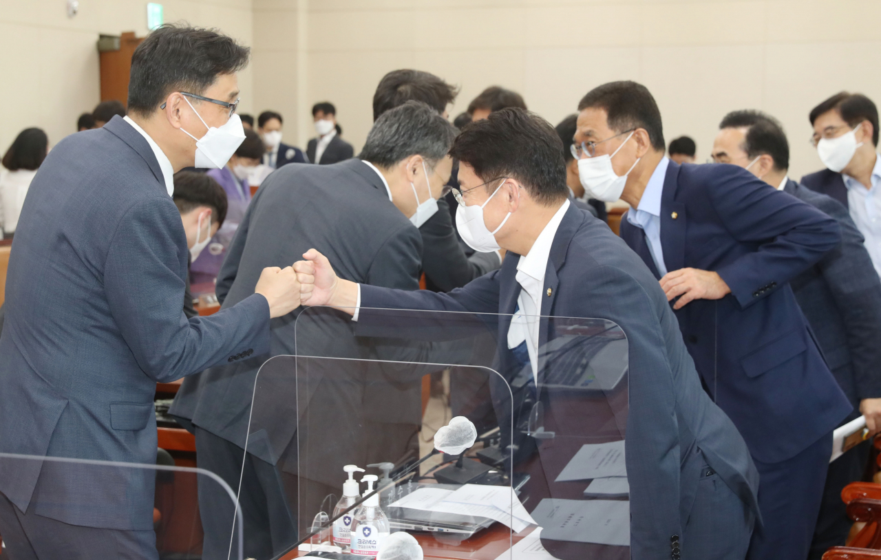 더불어민주당과 국민의힘 의원들이 19일 서울 여의도 국회 기획재정위원회 전체회의에서 종부세 '과세기준 11억' 상향 개정안을 통과시킨 뒤 주먹을 맞대고 있다. [연합]