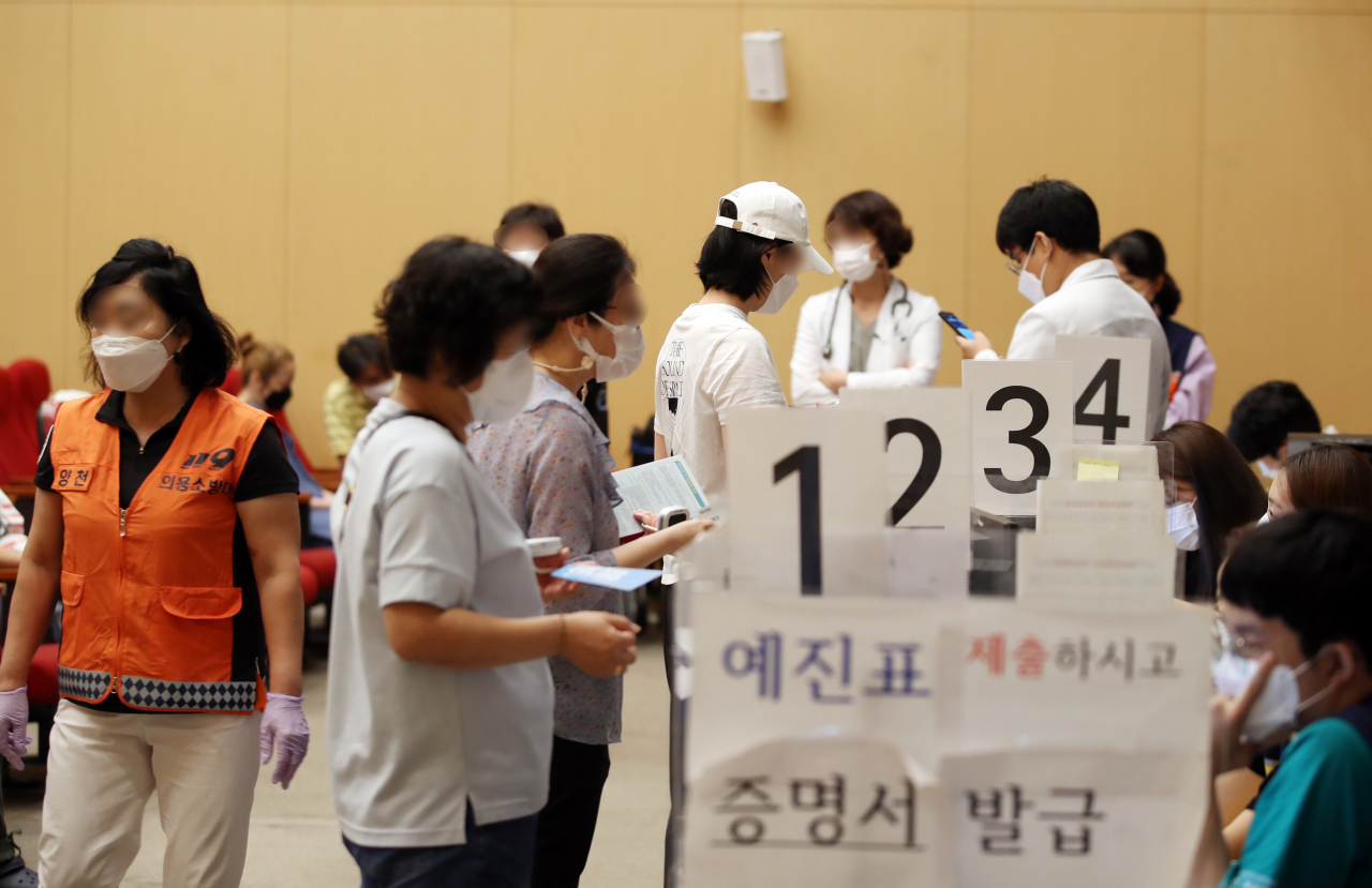 20일 오전 서울 양천구 예방접종센터에서 시민들이 백신 접종 뒤 증명서를 발급받고 있다. [연합]