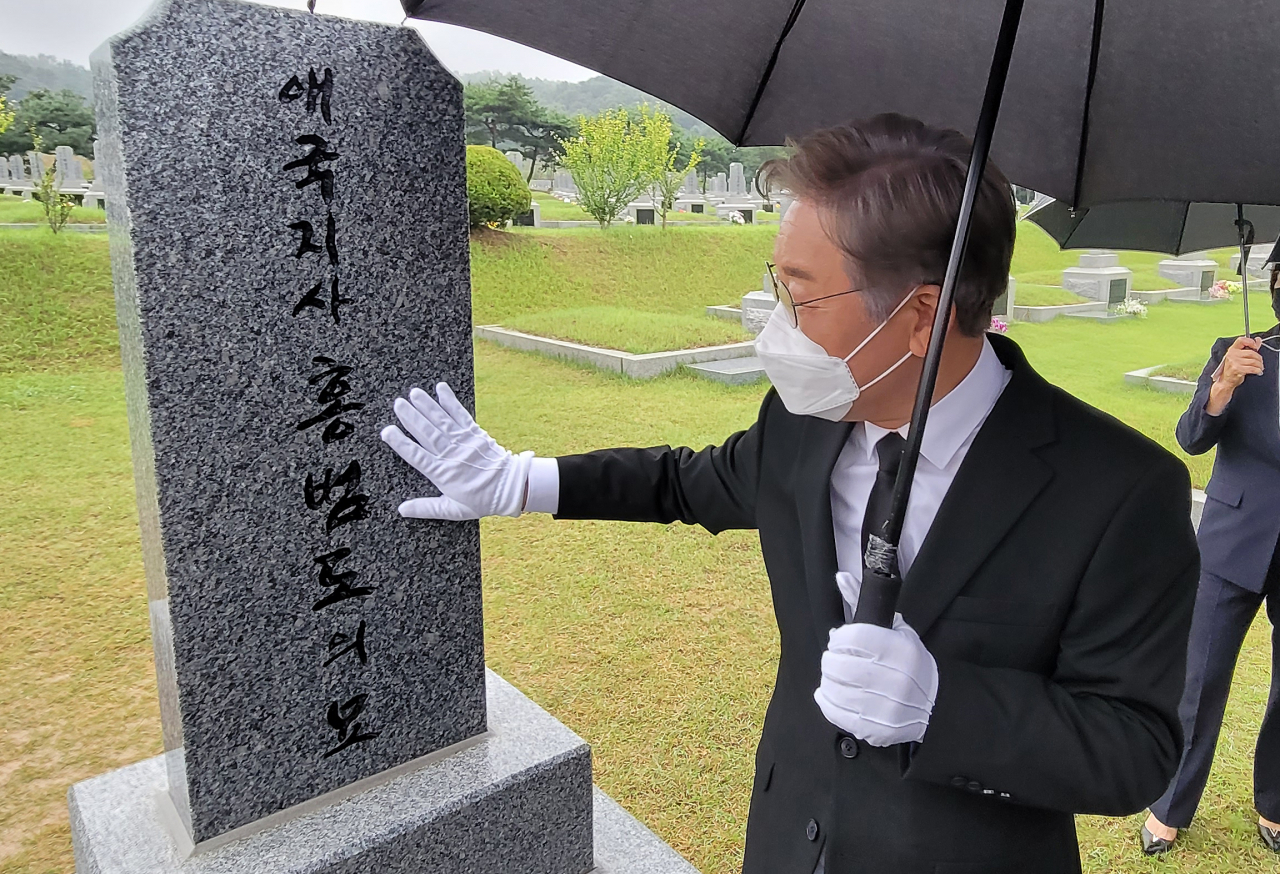더불어민주당 대권주자인 이재명 경기지사가 21일 오전 국립대전현충원에 있는 홍범도 장군 묘역을 찾아 참배한 뒤 묘비를 어루만지고 있다. [연합]