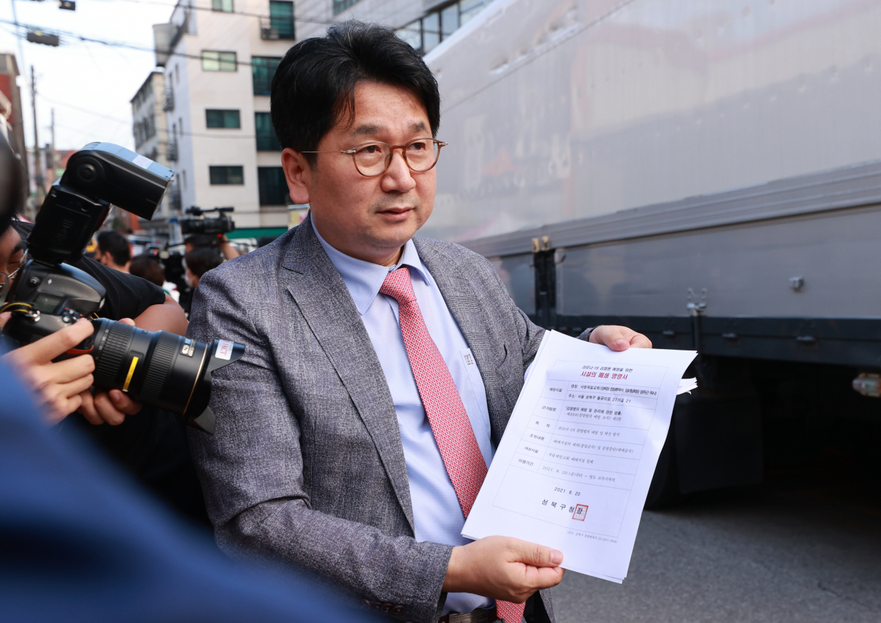 사랑제일교회 측 이성희 변호사가 19일 오후 서울 성북구 사랑제일교회 앞에서 성북구청 문화체육과로부터 수령한 시설 폐쇄 명령서를 취재진에게 보여주고 있다. 서울 성북구는 이날 신종 코로나바이러스 감염증 방역수칙 위반과 운영중단명령 위반을 이유로 사랑제일교회에 대한 시설폐쇄를 결정했다. [연합]