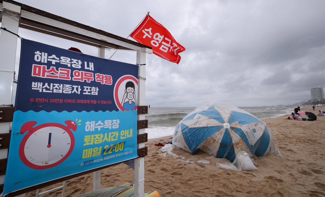 여름휴가철이 막바지에 접어든 지난 18일 오후 강릉 경포해변에 마스크착용 안내문이 붙어 있다. [연합]