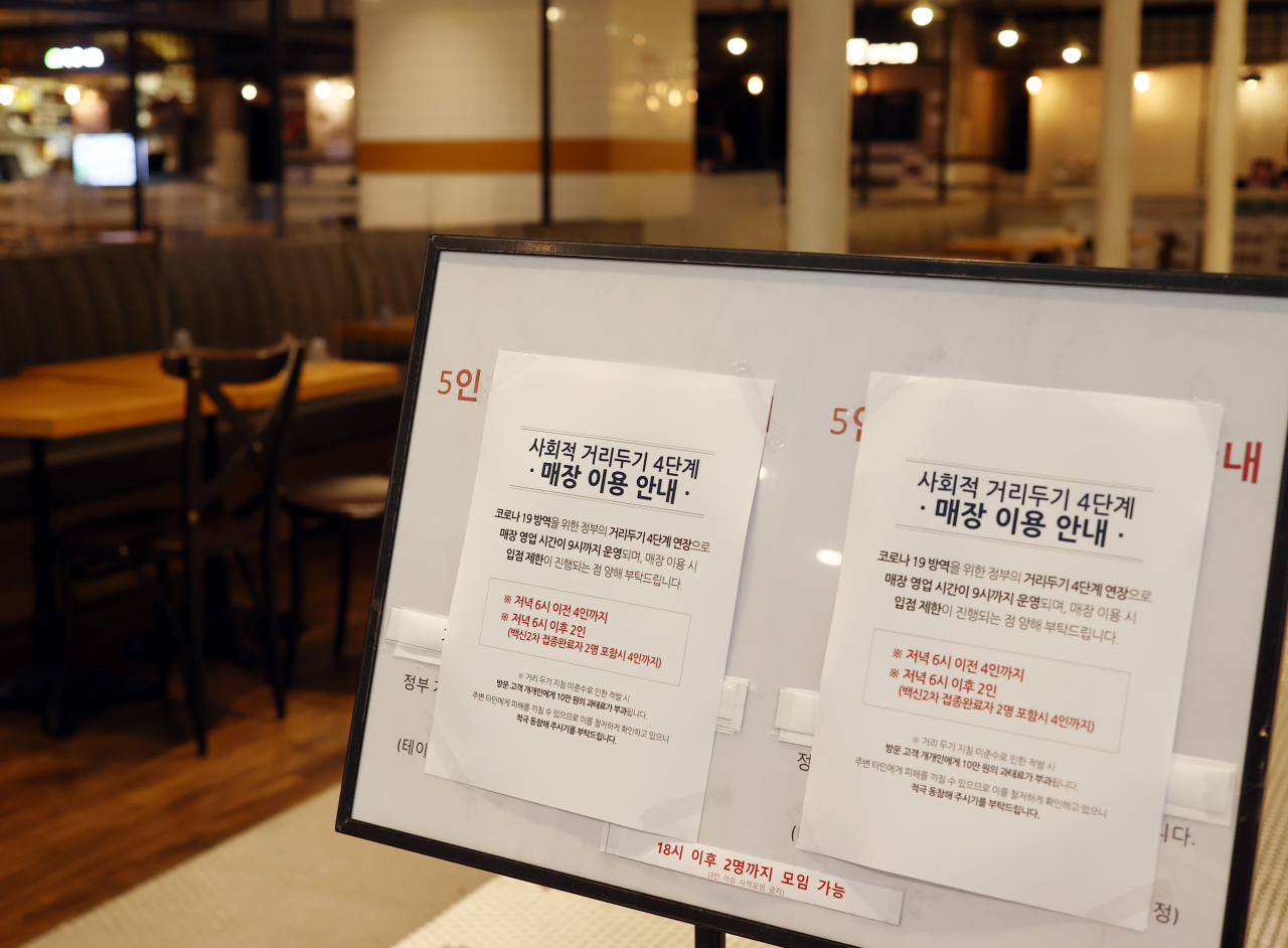 22일 오후 서울의 한 식당가에 코로나19 방역을 위한 정부의 거리두기 4단계 연장과 관련된 안내문이 붙어 있다. 정부는 오는 23일부터는 마스크를 쓰기 어려운 식당과 카페의 경우 4단계 지역에서는 매장 영업시간을 오후 10시에서 9시까지로 1시간 단축하기로 했다. 다만 접종 완료자에 대해서는 식당·카페 이용시 5인 미만 범위에서 사적모임 인원 산정 때 제외해 주기로 했다. [연합]