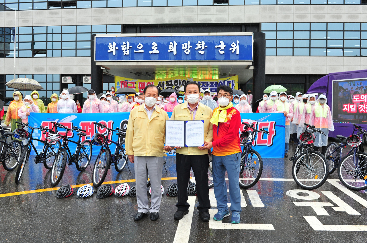 박한배 군위군 통합신공항 추진위원장(오른쪽)이 23일 오후 군위군청 앞에서 김영만 군수(가운데)와 심칠 군의장에게 ‘군위군 대구 편입 찬성촉구 성명서’를 발표한 뒤 이를 전달했다.[군위군 제공]