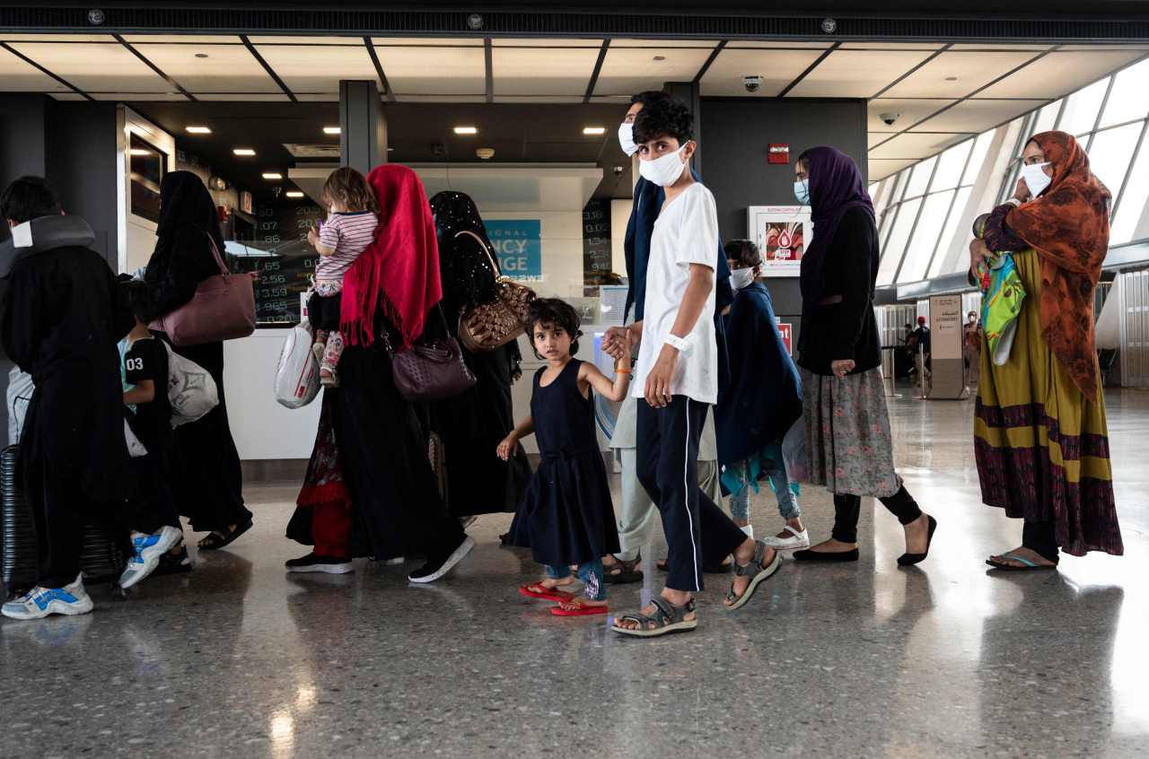 Refugees from Afghanistan are escorted to a waiting bus after arriving and being processed at Dulles International Airport in Dulles, Virginia on Monday. (AFP-Yonhap)
