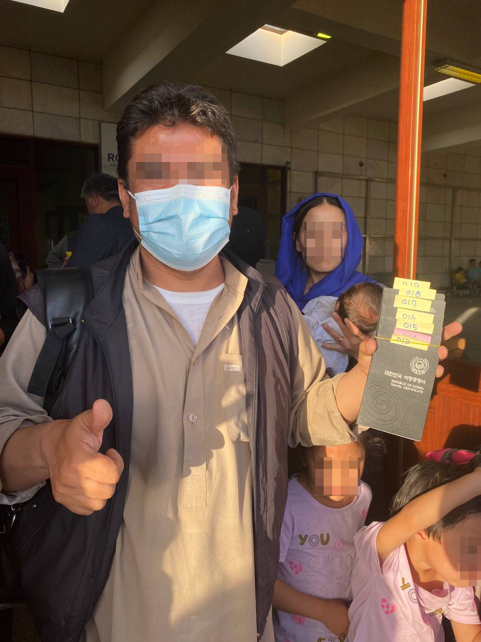 한국 정부와 협력한 아프가니스탄인이 카불공항에 도착한 공군 수송기에 탑승하기 전 외교부가 발행한 여행증명서를 들어보이며 기뻐하고 있다. [연합]