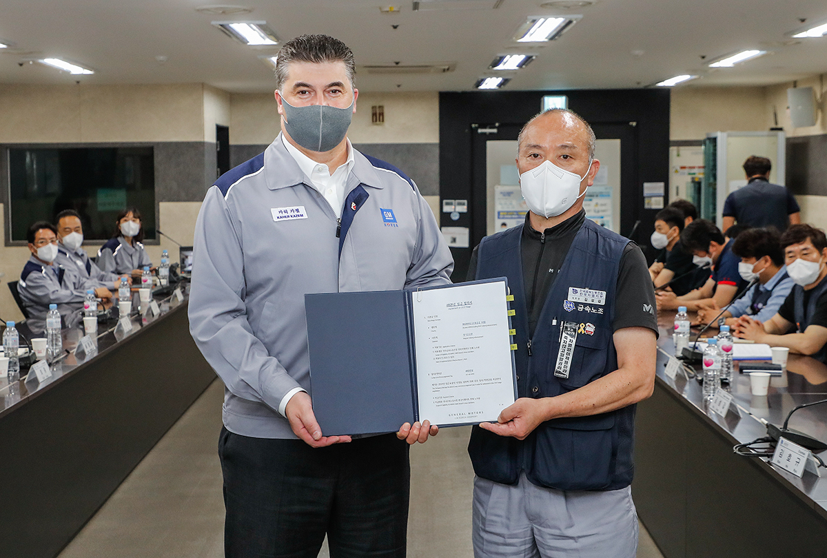 한국지엠주식회사 노사가 27일 2021년 임금협상 합의안에 대한 조인식을 갖고 올해 임금 교섭을 공식 마무리했다. 카허 카젬 한국지엠 사장(왼쪽)과 금속노조 한국지엠지부 김성갑 지부장(오른쪽)이 합의서를 들고 기념 촬영을 하고 있다. [한국지엠 제공]