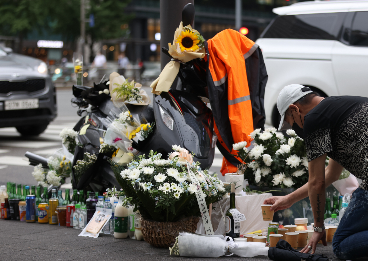 27일 오후 서울 강남구 선릉역 인근 도로에 전날 사망한 오토바이 배달원을 추모하는 국화꽃 등이 놓여져 있다. 오토바이 배달원은 전날 오전 신호를 기다리다 화물차에 치여 숨졌다. 민주노총 서비스연맹 서비스일반노조 이날 추모 행사를 열고 이 사고를 산업재해로 인정해줄 것을 촉구했다. [연합]