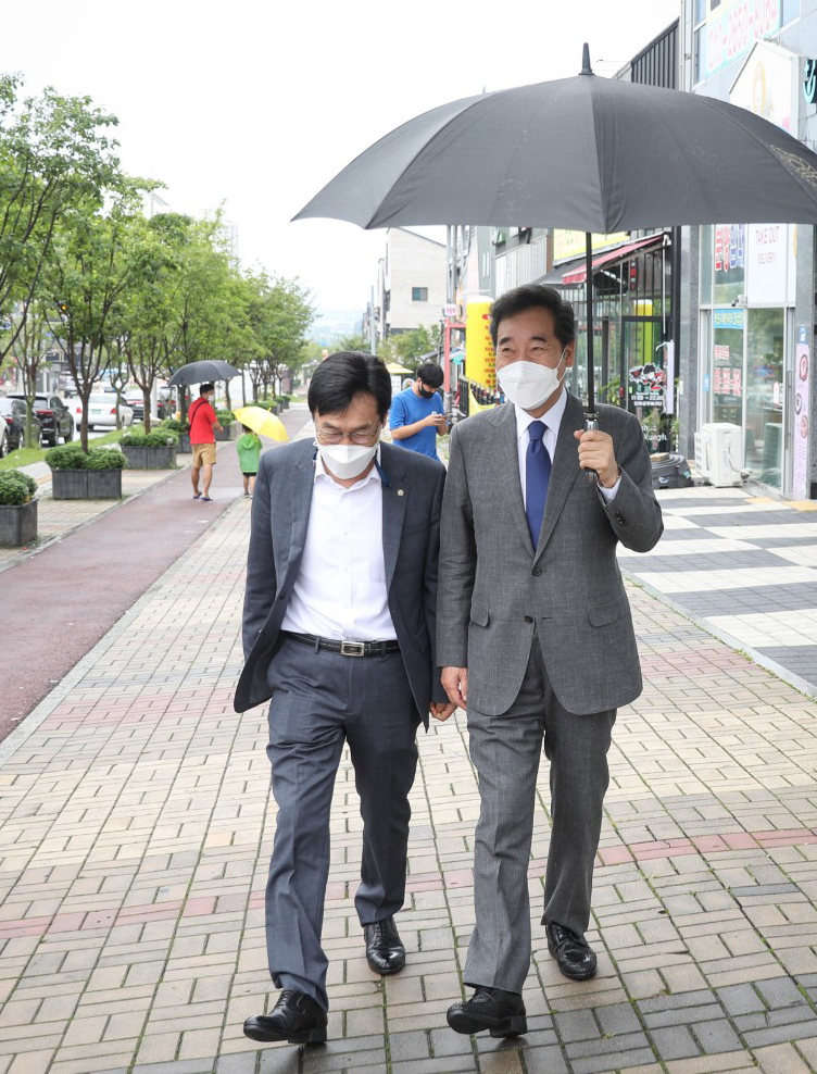 더불어민주당 대권주자인 이낙연 전 대표가 29일 충북 음성군 맹동면 임호선 국회의원 지역사무소에서 중부3군 핵심당원 간담회를 마치고 직접 우산을 들고 이장섭 의원과 함께 걷고 있다. [연합]