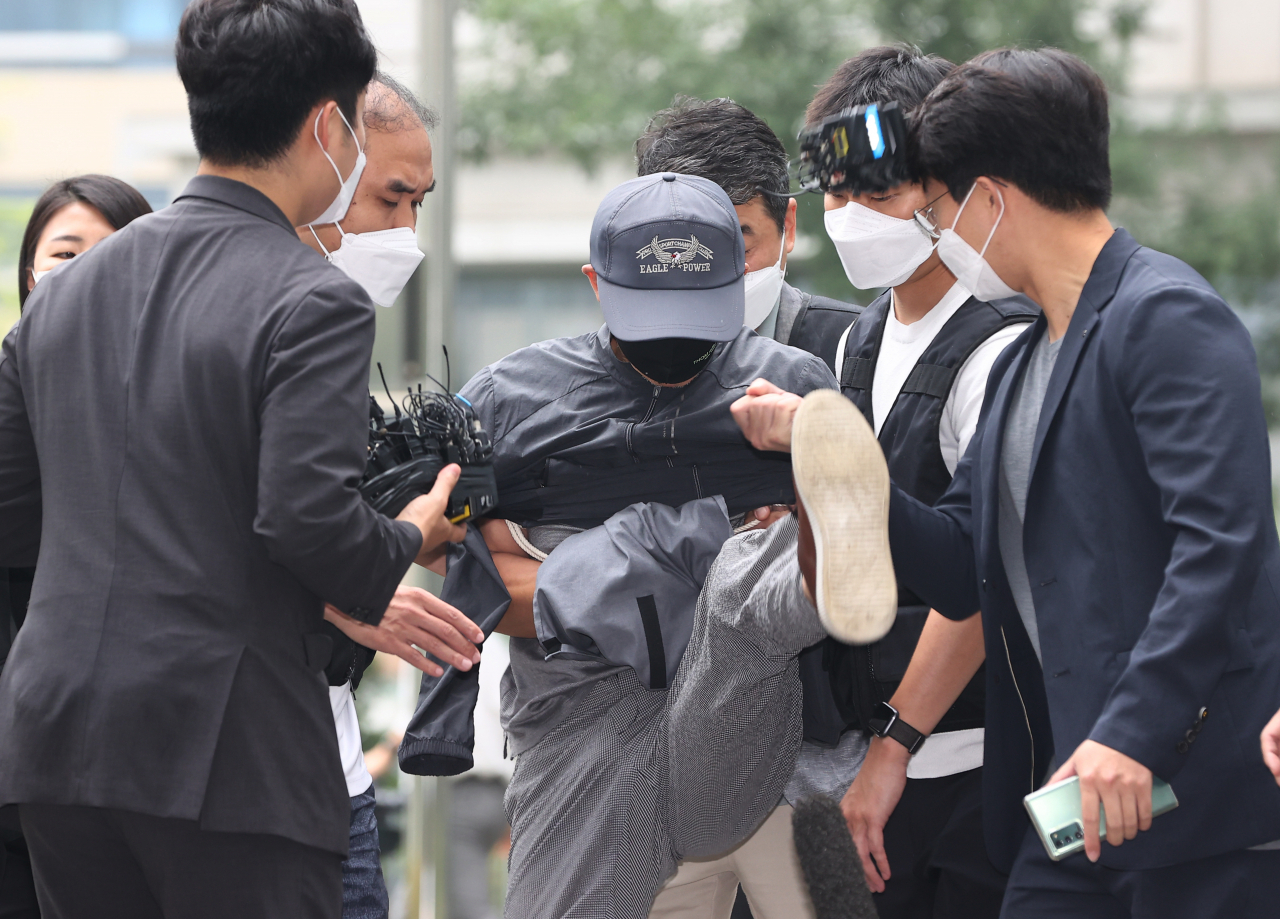 위치추적 전자장치(전자발찌) 훼손 전후로 여성 2명을 잇달아 살해한 혐의를 받는 강모 씨가 31일 서울동부지법에서 열리는 영장실질심사에 출석하던 중 질문을 하려는 취재진의 마이크를 발로 걷어차고 있다. [연합]