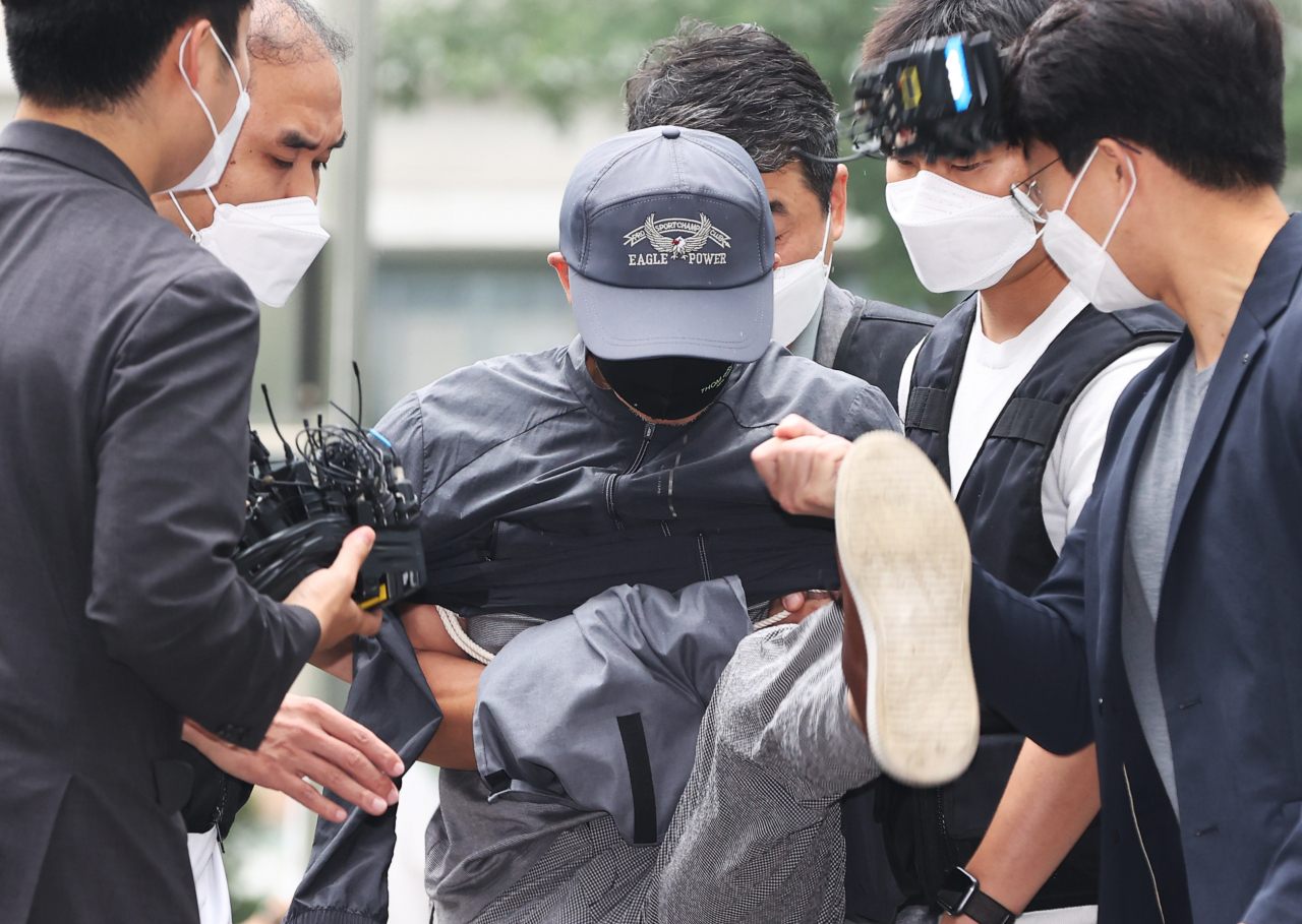 위치추적 전자장치(전자발찌) 절단 전후로 여성 2명을 살해한 혐의를 받는 강모 씨가 지난달 31일 서울동부지법에서 열리는 영장실질심사에 출석하던 중 질문을 하려는 취재진의 마이크를 발로 걷어차고 있다. [연합]