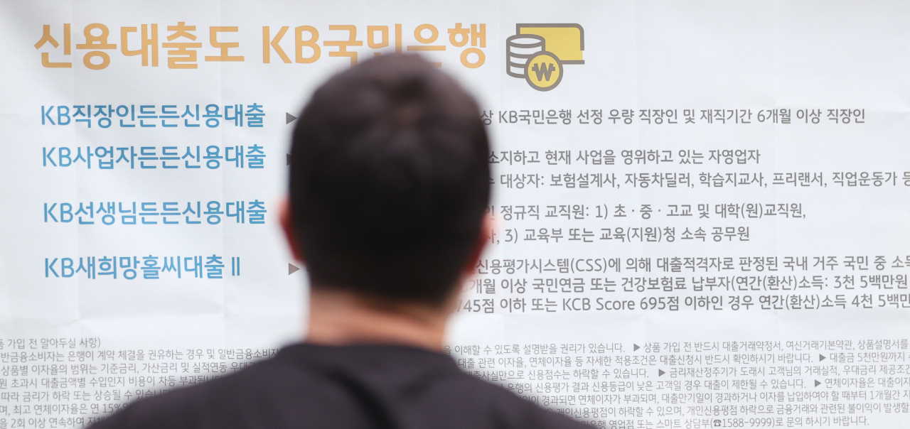 KB·신한·하나·우리·NH농협 5대 은행과 외국계 씨티·SC제일은행, 인터넷은행 카카오뱅크·케이뱅크 등이 지난 27일 금융감독원에 신용대출 상품 대부분의 최대한도를 연소득 이내로 줄이겠다는 계획을 제출한 것으로 알려진 가운데 30일 오후 서울의 한 시중 은행 앞에서 시민이 신용대출 상품 관련 현수막을 유심히 보고 있다. [연합]
