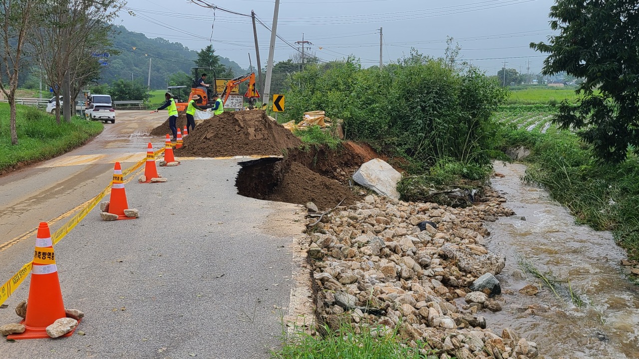 Workers repair roads that were damaged in the rain in Hongseong, North Chungcheong Province on Wednesday. (Yonhap)