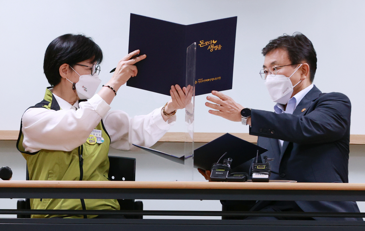 나순자 보건의료노조 위원장(왼쪽)과 권덕철 보건복지부 장관이 2일 새벽 서울 영등포구 의료기관평가인증원에서 전국보건의료산업노동조합과 보건복지부의 13차 노정실무교섭이 타결된 뒤 서명한 합의문을 교환하고 있다.[연합]