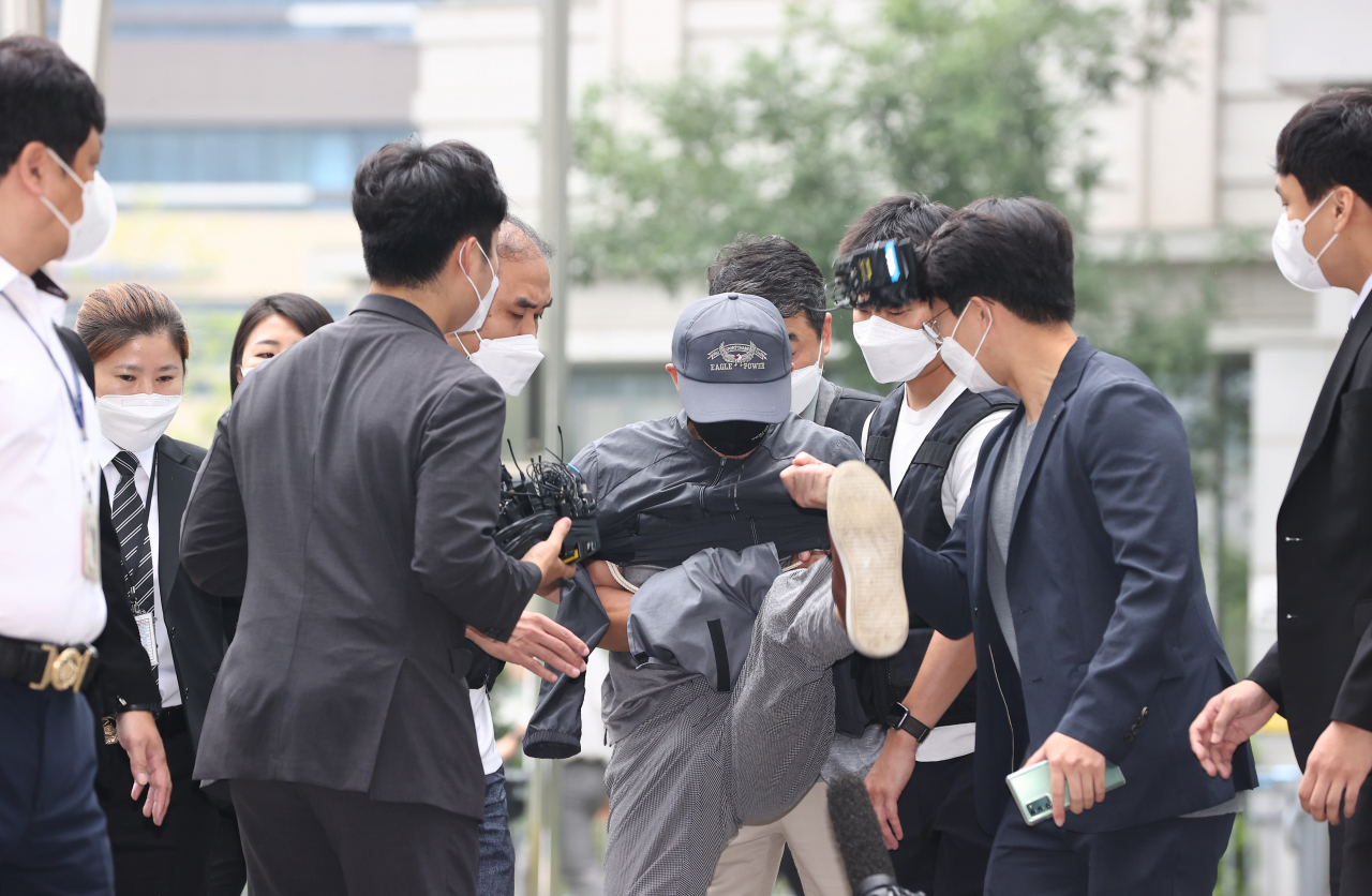 위치추적 전자장치(전자발찌) 훼손 전후로 여성 2명을 잇달아 살해한 혐의를 받는 강윤성이 지난 8월 31일 서울동부지법에서 열리는 영장실질심사에 출석하던 중 질문하려는 취재진의 손과 마이크를 발로 걷어차고 있다. [연합]