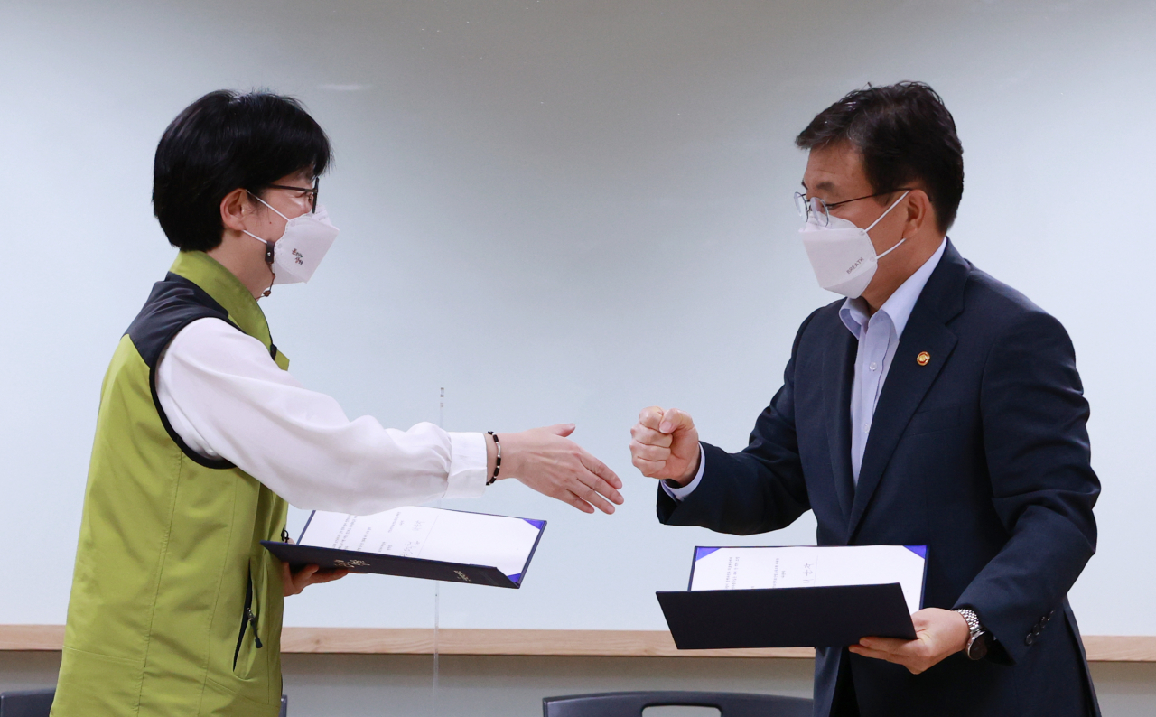 나순자 보건의료노조 위원장(왼쪽)과 권덕철 보건복지부 장관이 2일 새벽 서울 영등포구 의료기관평가인증원에서 전국보건의료산업노동조합(보건의료노조)과 보건복지부의 13차 노정실무교섭이 타결된 뒤 서명한 합의문을 교환하며 인사하고 있다. [연합]